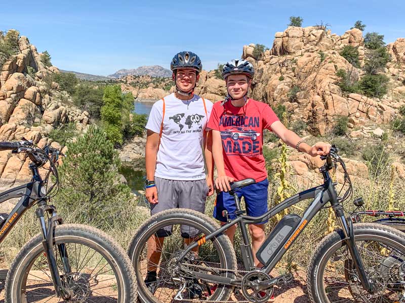 Young Men Posing for Photo with Ebikes in front of Scenic Lake View