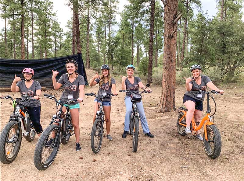 Group of Women Posing for Photo on Ebikes in Forest