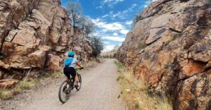 Woman Riding Down Trail Between Two Granite Rock Walls