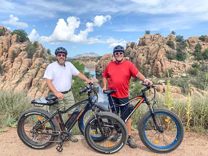 Men Standing Next to Ebikes on Trail with Scenic Lake View