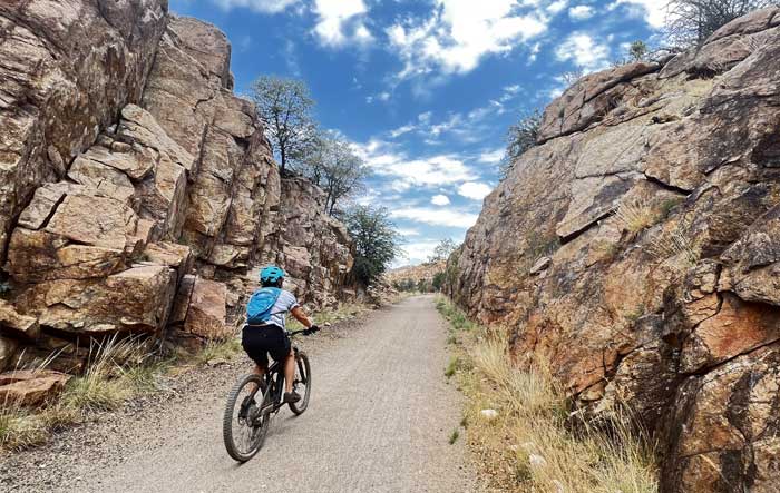 Woman Riding Down Trail Between Two Granite Rock Walls
